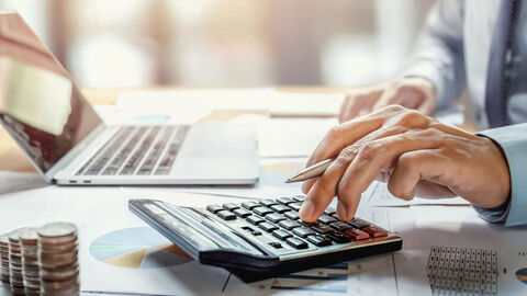 Geschäftsmann arbeitet am Schreibtisch an einer Kalkulation