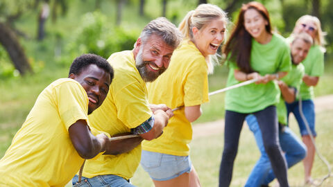 Eine Gruppe von fröhlichen Menschen ziehen an einem Seil